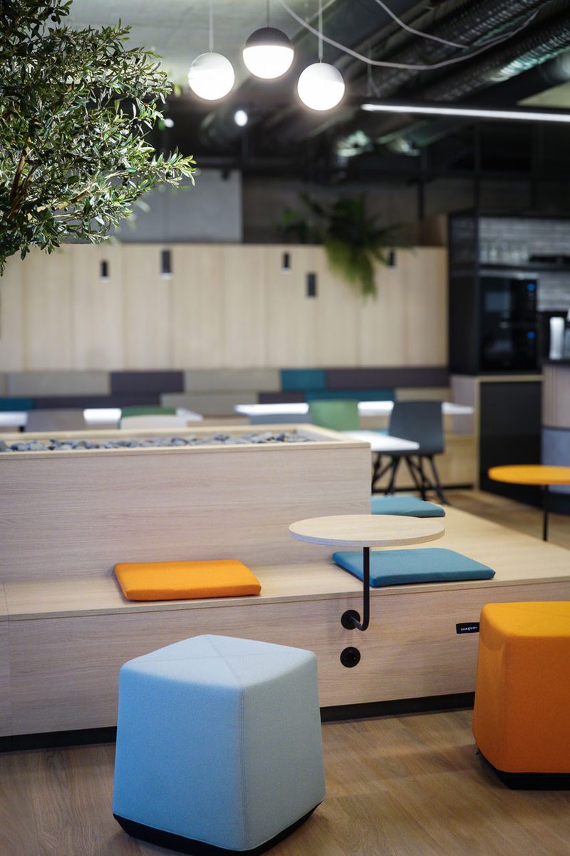 Sitzlandschaft aus hellem Holz mit farbigen Polstern in Blau, Gelb und Orange