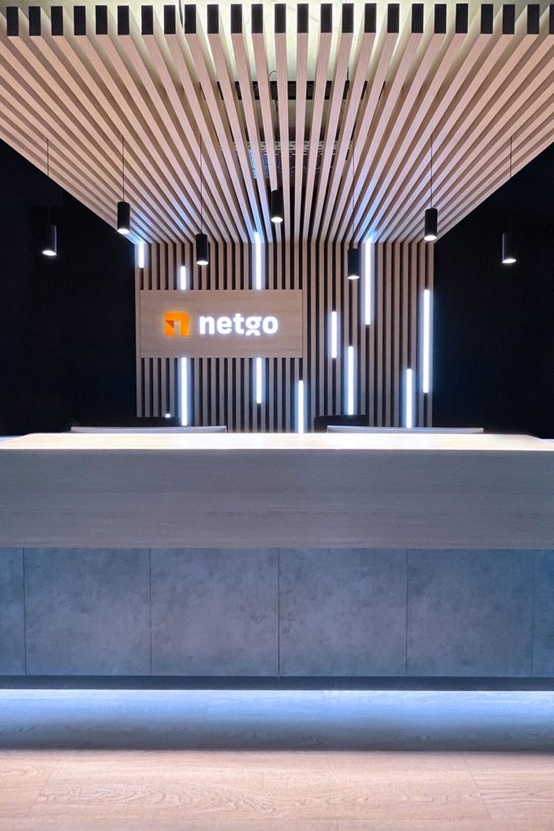 Empfangstresen vor einer Wand aus Holzlamellen mit beleuchtetem netgo-Logo
