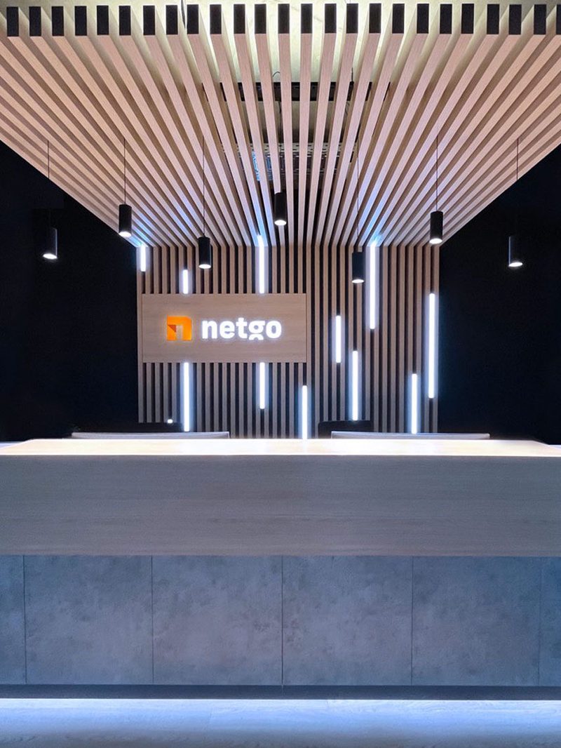 Empfangstresen vor einer Wand aus Holzlamellen mit beleuchtetem netgo-Logo