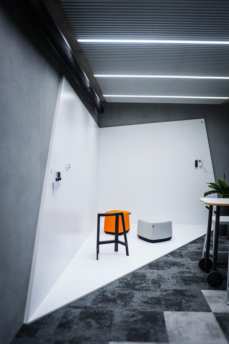 Heller Raum mit orangem Hocker, Stehtisch und Pflanze